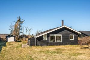 a black house sitting on top of a field at Rent A Cozy Holiday Home At Pirupshvarrevej 5A! in Blokhus