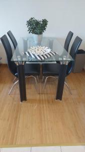 a glass table with black chairs and a potted plant at Apartman Trebinje sa parkingom in Trebinje