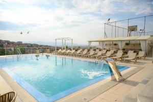 a swimming pool with chairs and a water slide at Hotel Tami Residence in Niš