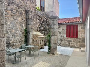 a patio with two tables and chairs next to a building at Hotel Recanto do Avia in Ribadavia