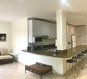 a kitchen with a bar with chairs and a couch at Vacation home in an exclusive private development in Higuerote