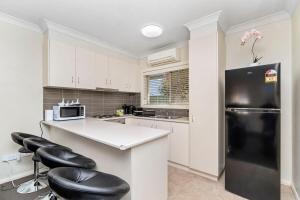 a kitchen with white cabinets and a black refrigerator at Wagga CBD Apartments in Wagga Wagga