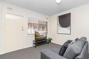 a living room with a couch and a flat screen tv at Wagga CBD Apartments in Wagga Wagga