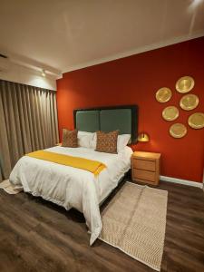 une chambre avec un grand lit avec un mur rouge dans l'établissement Menlyn Maine Trilogy Apartment 1316 & 1316A, à Pretoria 18 autres photos