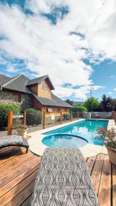 a swimming pool on a wooden deck with two chairs at Hosteria y Cabañas Posada Quinen in San Martín de los Andes