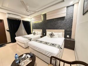 イスラマバードにあるTRH-The Rest Houseのベッド2台とテーブルがあるホテルの部屋