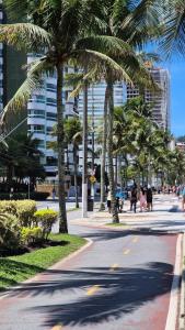 a street with palm trees and people walking down a street at Apto 2 dorms, suíte, 82 m2, a 90 metros da praia Vila Tupy, Praia Grande-SP in Praia Grande