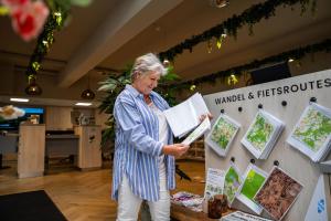 eine ältere Frau liest ein Buch in einem Geschäft in der Unterkunft Resort de Brabantse Kempen in Lage Mierde + 24 Fotos