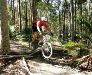 Ein Mann, der im Wald Fahrrad fährt in der Unterkunft Pemberton Lake View Chalets in Pemberton