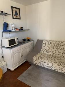勒卡特港Appartement F2 agréable avec terrasse的小房间设有床铺和微波炉 更多3张照片