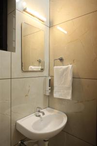a bathroom with a white sink and a mirror at Greens Residency in Tripunnittara