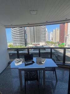 Flat Beira Mar - Fortaleza في فورتاليزا: طاولة عليها جهاز كمبيوتر محمول أمام النافذة +19 صورة