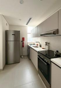 a kitchen with a stainless steel refrigerator and a sink at By The Beach - Prime location in Sarūq