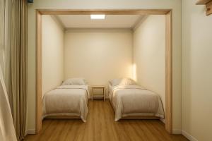 two beds in a small room with a table at Vila Dorathea in Blumenau