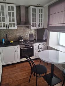 a kitchen with white cabinets and a table and chairs at Уютная 2-х комнатная квартира in Rudny