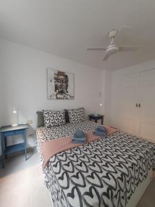 Un dormitorio con una cama con un edredón blanco y negro. en Alquilaencanarias Medano Lago Azul, en El Médano