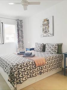 Un dormitorio con una cama con un edredón blanco y negro. en Alquilaencanarias Medano Lago Azul, en El Médano