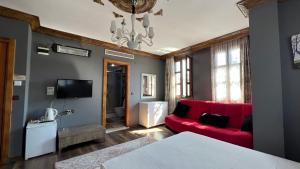 Una sala de estar con un sofá rojo y un televisor. en La Fontaine Otel, en Mudanya