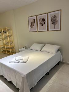 a bedroom with a large white bed with three pictures on the wall at Flats do Vale in Petrolina