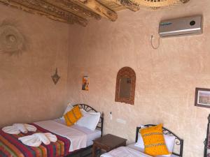 a room with two beds in a room with a fan at Riad Dades Birds in Boumalne +87 photos