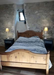 1 dormitorio con 1 cama de madera y 2 lámparas en las mesas en Ferme Des Montagnes Bleues, en Jonchères