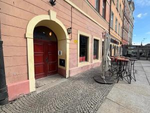 a building with a red door and a table with an umbrella at Central Lux Apartment - Heart of the Old Town Check In 24h in Wrocław