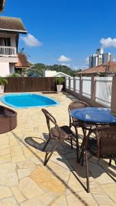un patio con tavolo e sedie e una piscina di Suíte próximo a Vila Germânica a Blumenau