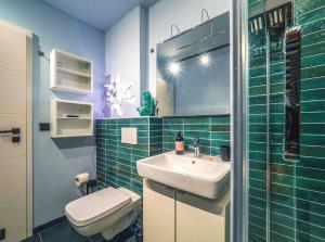 a green tiled bathroom with a sink and a toilet at Wunderschönes Loft-Apartment im grünen Hamburg in Hamburg