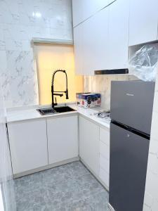 a white kitchen with a sink and a refrigerator at Luxury 1BR apartment with free wifi in Lagos