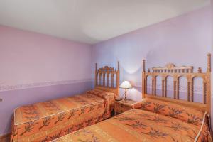 a bedroom with two beds and a table with a lamp at El Rellano in Maluenda