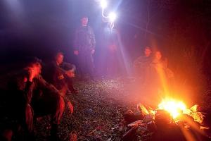 a group of people standing around a fire at night at Projeto Puma in Lages