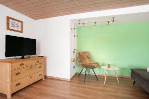 オーバーロイテにあるFerienwohnung Harmonieのリビングルーム(テレビ、ドレッサー、椅子付)