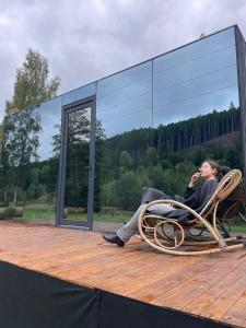 a woman sitting in a wicker chair on a deck at Wellness Retreat Glamping - Adults Only - Forest & Valley in Pirkenhammer +5 photos