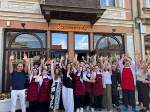 a group of people standing in front of a building with their hands up at Oysters & Bubbles Gastro Rooms Rynek Square in Poznań +4 photos