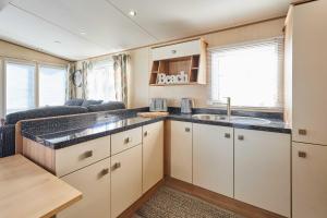 - une cuisine avec des placards blancs et un évier dans une caravane dans l'établissement Host & Stay - Leon's Retreat, à Cresswell