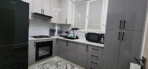 a small kitchen with white cabinets and a microwave at Zara premium apartment 66 in Stantsiya Kyzyl-Tukumachi