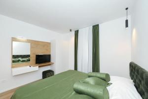 a bedroom with a green bed and a television at Villa Vallis with pool in Kruševo