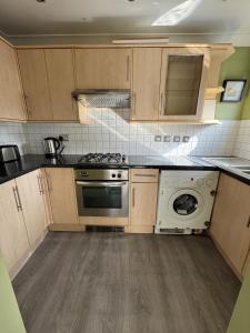 a kitchen with a stove and a washing machine at Comfortable, London 1 Bed Garden in London