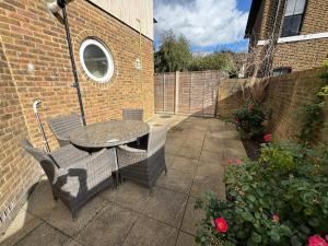 a patio with a table and chairs and a brick wall at Comfortable, London 1 Bed Garden in London