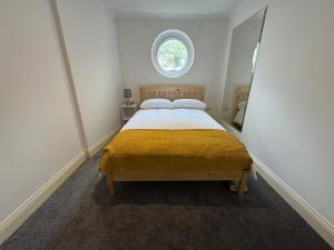 a bedroom with a bed with a yellow blanket at Comfortable, London 1 Bed Garden in London