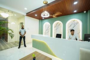 dos hombres parados en un mostrador en una habitación en Hotel Royal International - Best Boutique Hotel Near Airport & Kamakhya Temple, en Guwahati