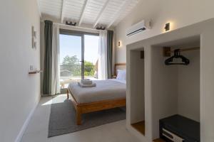 una camera da letto con un letto e una grande finestra di Naro Suites Alaçatı Köyiçi a Çeşme