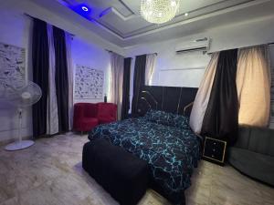 1 dormitorio con cama negra y silla roja en Effixzzy villa, en Lekki