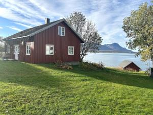 a red house on the shore of a body of water at House at the farm! in Tromsø
