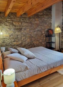 a bed with pillows in a room with a stone wall at Casa Rural Haiku in Bojar