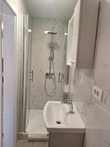 a white bathroom with a shower and a sink at Studio Apartmani in Rijeka +3 photos