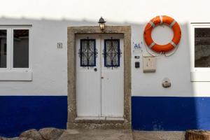 a white and blue building with a door and a life preserver at Charming Studio apartment in Sintra, Penedo in Colares +8 photos