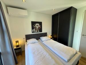 a bedroom with two beds and a dog picture on the wall at Enkhuizer Strand Chalet IJsselmeerblick Zweite Reihe mit Zaun Haus Nr 221 in Enkhuizen