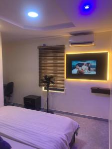 a bedroom with a bed and a tv on the wall at Cbox Lodge & Lounge in Lagos