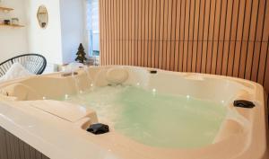 e bagno con vasca riempita di acqua verde. di Perce Neige Bien être a La Bresse